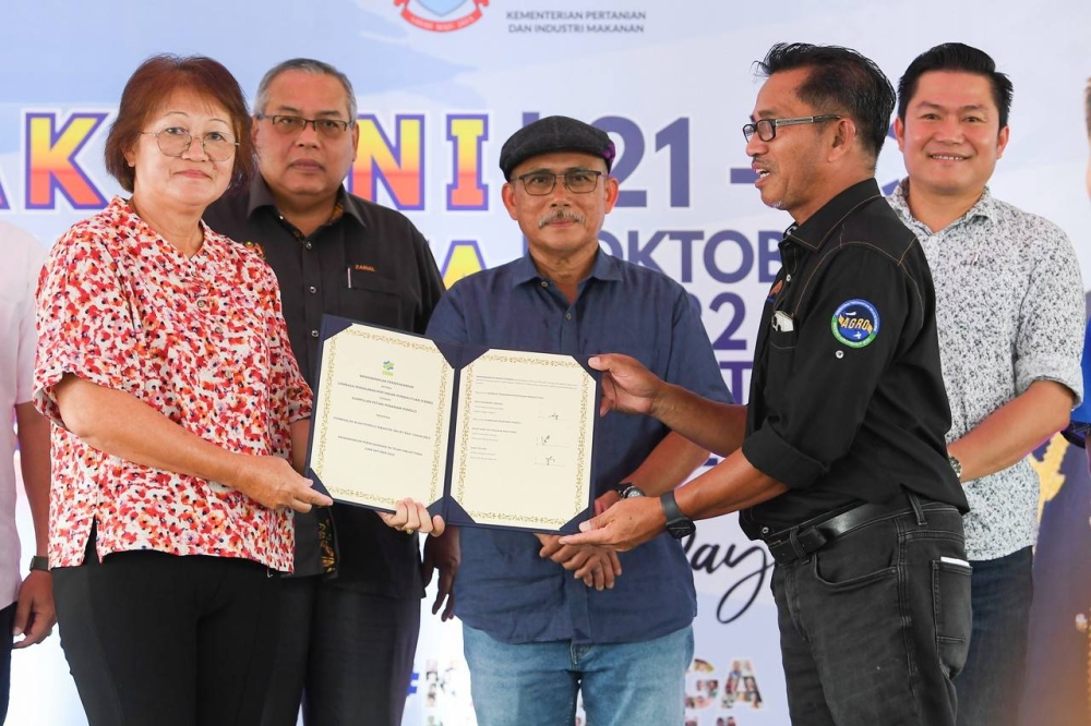 Minister of Agriculture and Food Industry Datuk Seri Dr Ronald Kiandee (centre) witnessing Fama Sabah Director Ribin Wahid handing over the Fama Entrepreneur agreement document in the marketing of Pamelo fruit to Fang Yin Fah in Telupid, Sabah, October 22, 2022. — Bernama pic