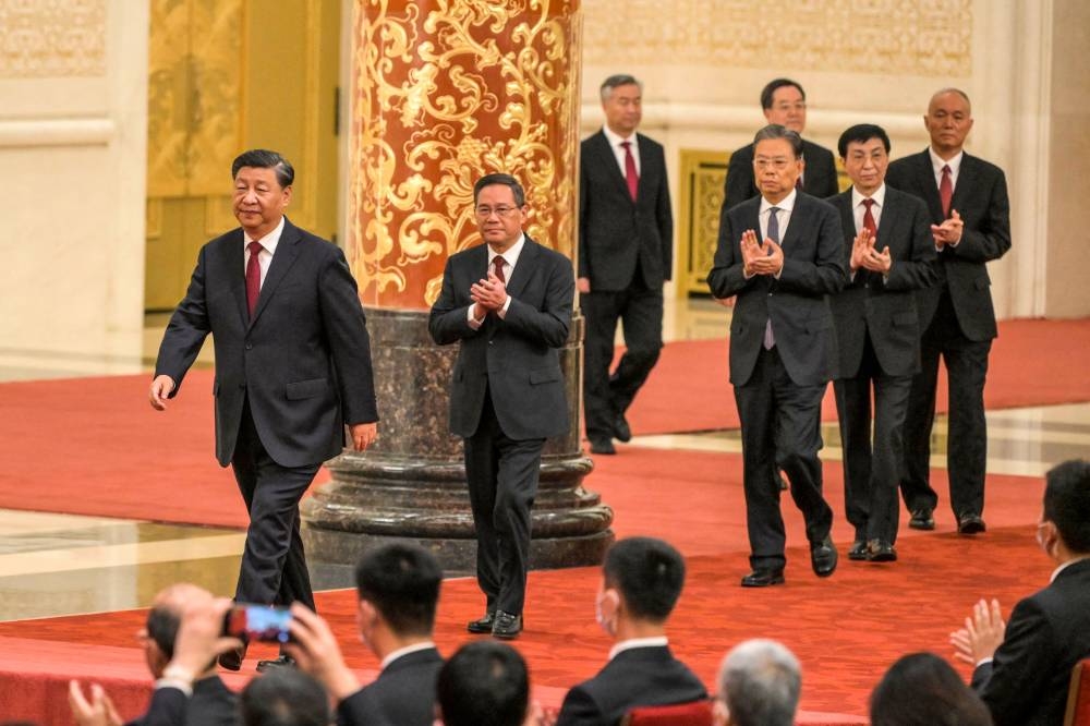 China's President Xi Jinping (left) walks with (second left to right) Li Qiang, Li Xi, Zhao Leji, Ding Xuexiang, Wang Huning and Cai Qi, members of the Chinese Communist Party's new Politburo Standing Committee, the nation's top decision-making body, as they meet the media in the Great Hall of the People in Beijing on October 23, 2022. — AFP pic