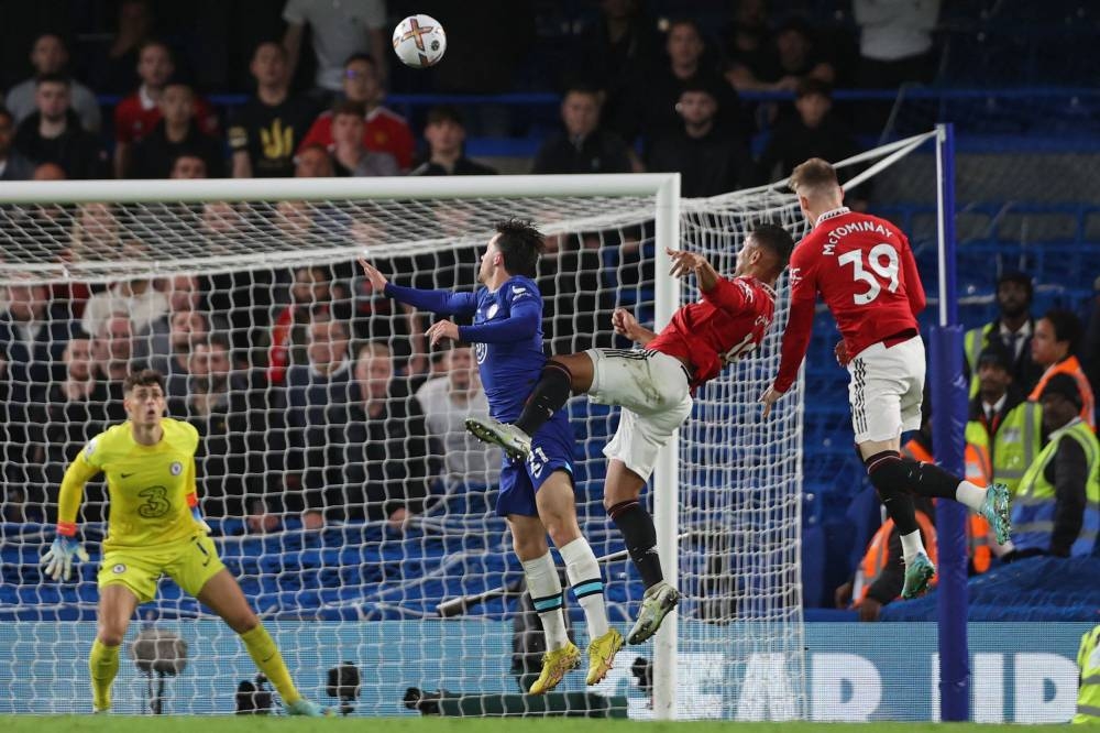 Manchester United's Brazilian midfielder Casemiro (2nd R) jumps in a crowd of players to head home their late equalizing goal during the English Premier League football match between Chelsea and Manchester United at Stamford Bridge in London on October 22, 2022. — AFP pic