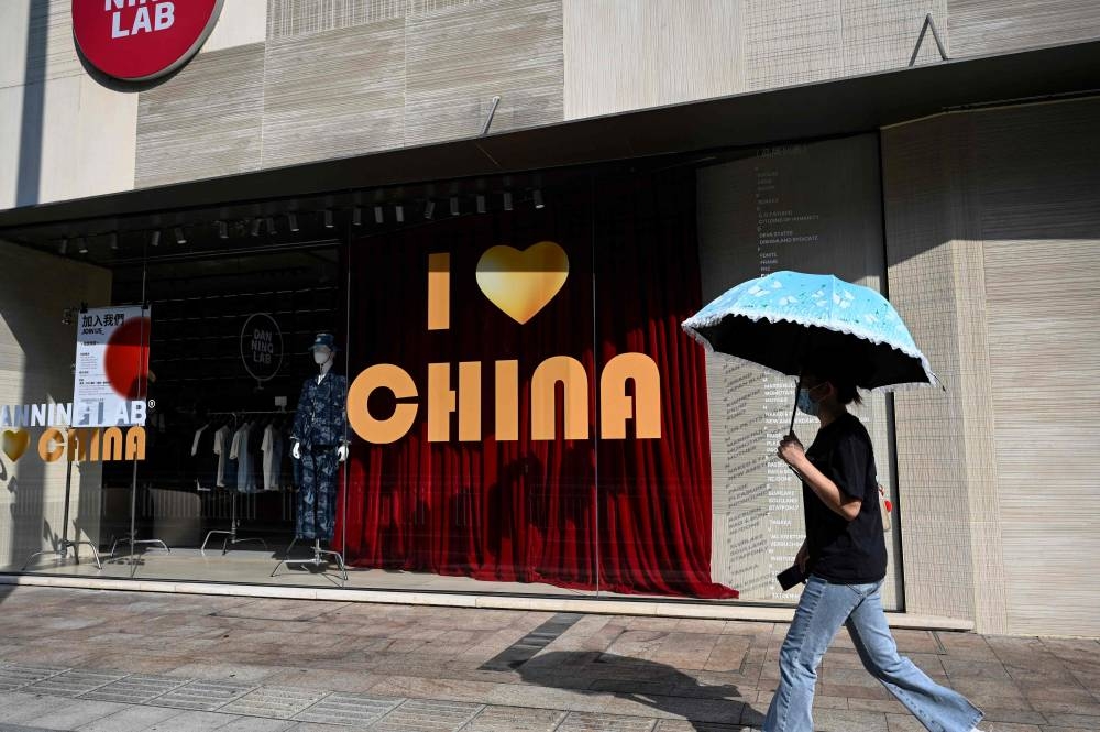 A woman walks past a clothing store in Foshan in southern China October 24, 2022. — AFP pic