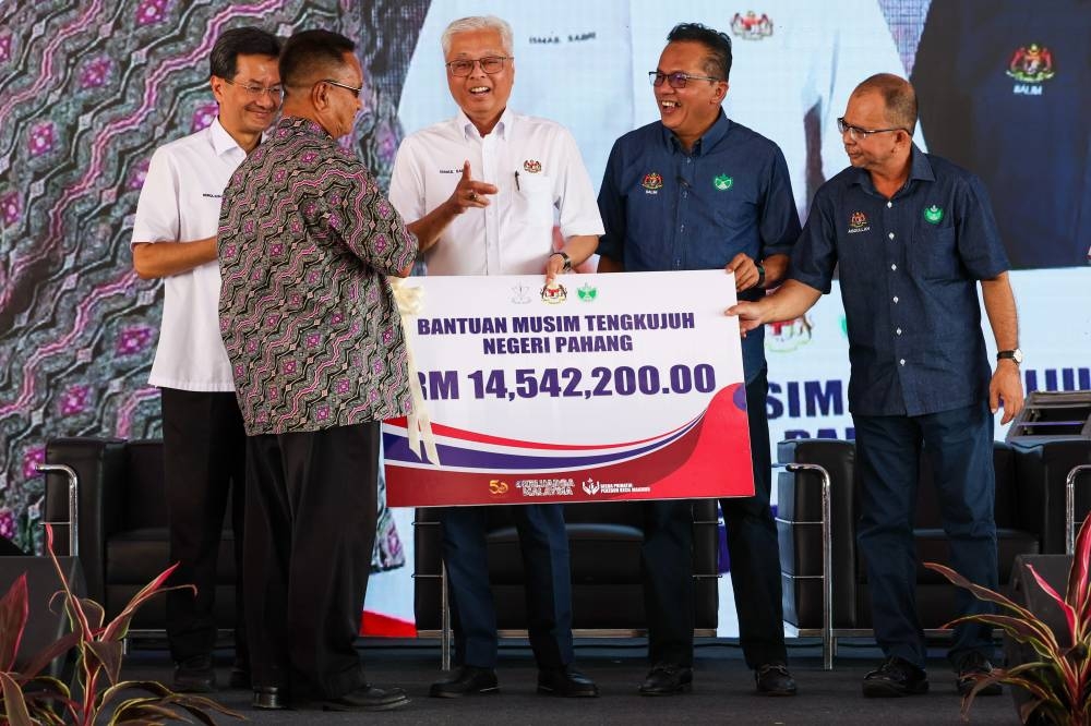 Prime Minister Datuk Seri Ismail Sabri Yaakob (centre) presenting a mock cheque of Pahang State Monsoon Assistance for smallholders amounting to RM14,542,200 to smallholder representative Mohd Rozali Jamaludin (second left) at the Makmur Smallholder Program organised by Rubber Industry Smallholder Development Authority (RISDA) in Kampung Batu Papan in Bera, October 29, 2022. — Bernama pic