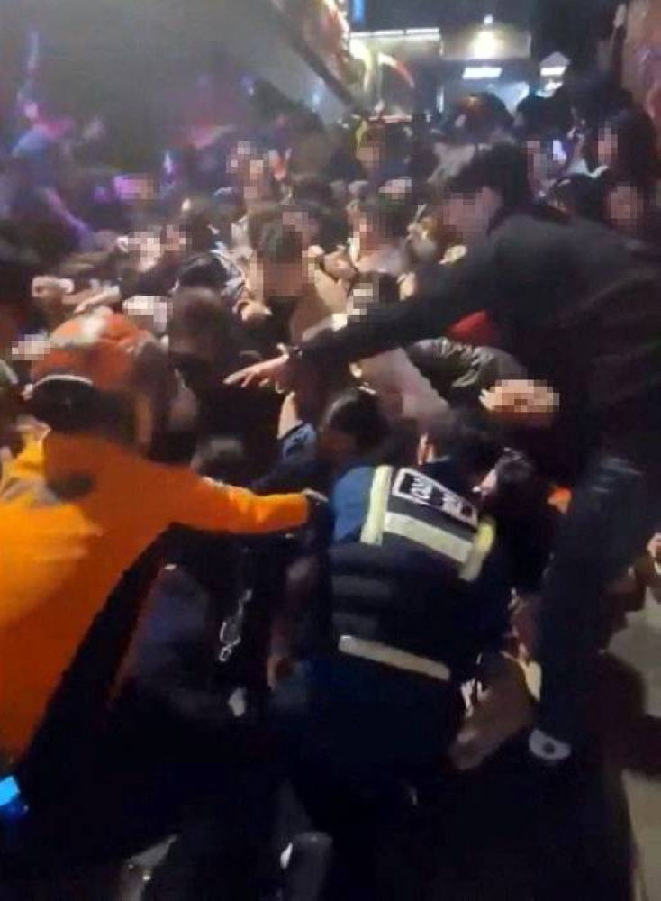 Rescue workers, policemen and civilians try to rescue people at the scene where a stampede during Halloween festivities killed and injured many people at the popular Itaewon district in Seoul, South Korea, in this image released by Yonhap on October 30, 2022. — Yonhap pic via Reuters