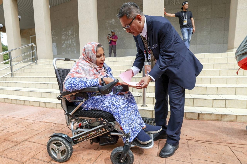 A disabled professional (OKU) who is also a Pakatan Harapan candidate, Dr Noraishah Mydin Abdul Aziz (left) is assisted by the Putrajaya P125 Parliamentary Election Deputy Manager, Marzuan Ismail at the P125 Putrajaya Parliamentary Candidate Nomination Center, November 5, 2022. — Bernama pic