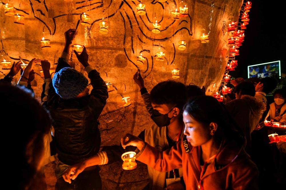 This photo taken on November 6, 2022 shows revellers preparing lanterns to attach to hot-air balloons during the Tazaungdaing Lighting Festival at Pyin Oo Lwin Township in Mandalay. — AFP pic