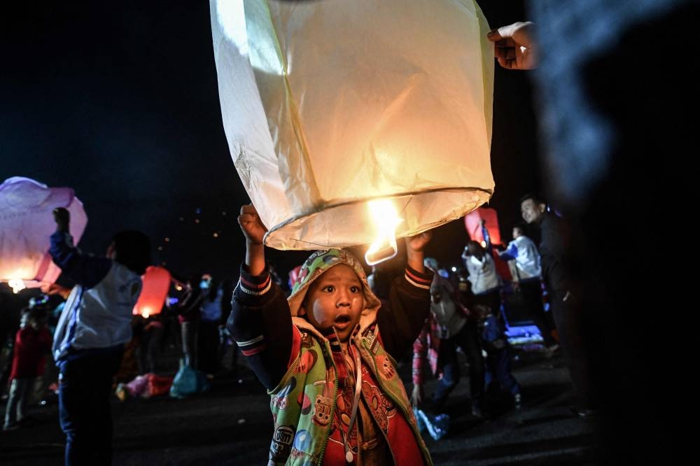 This photo taken on November 6, 2022 shows a boy releasing a small hot-air balloon during the Tazaungdaing Lighting Festival at Pyin Oo Lwin Township in Mandalay. — AFP pic