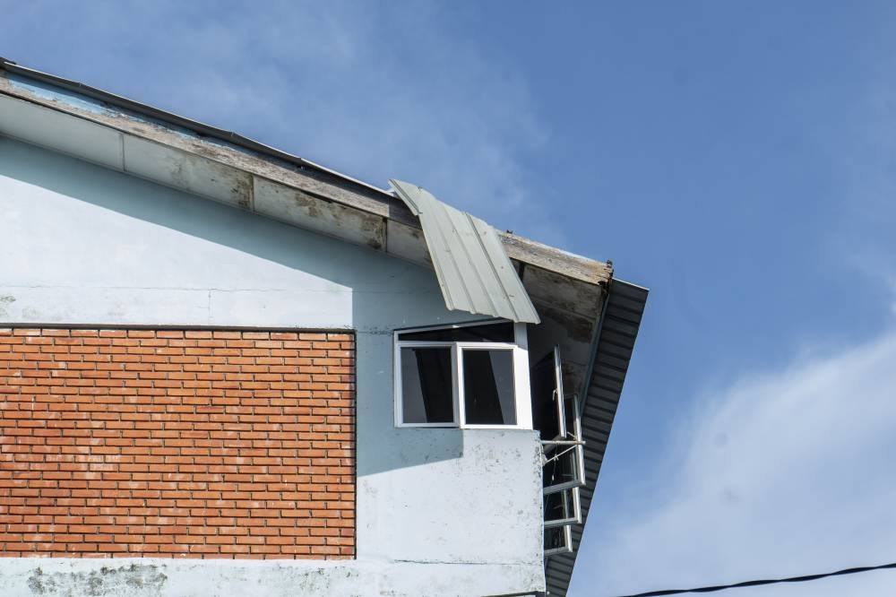 Loose zinc sheets dangle from the rooftop of Rumah Pangsa Simpang Kuala pose a hazard to those passing below. 