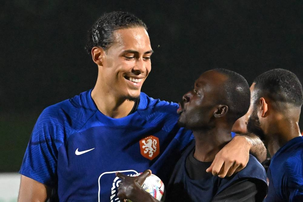 Netherlands' defender Virgil van Dijk embraces a player from a football team of the delegation of workers during a training session at Qatar University training site 6 in Doha on November 17, 2022, ahead of the Qatar 2022 World Cup football tournament. — AFP pic