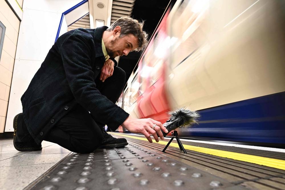 Musician and sound artist Stuart Fowkes records the sound of a passing London Underground train at Blackfriars tube station in London on November 28, 2022. — AFP pic