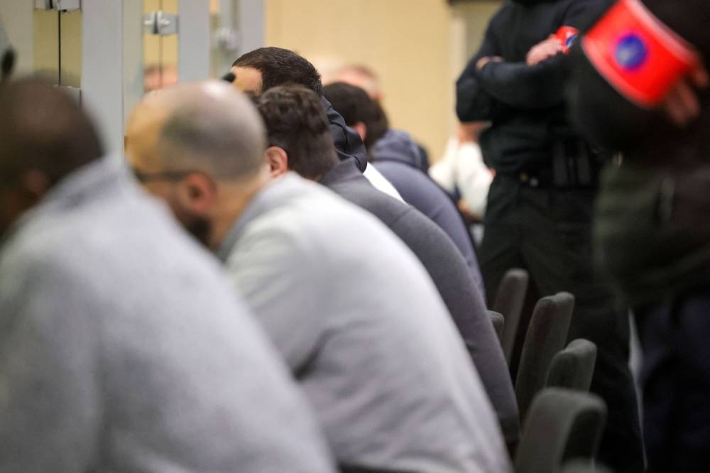 Special police stand behind defendants in a specially designed glass box during the start of the trial for the Brussels attacks, that took place on March 22, 2016, at the Justitia building in Brussels, Monday, Dec. 5, 2022. — Olivier Matthys/Pool/Reuters pic