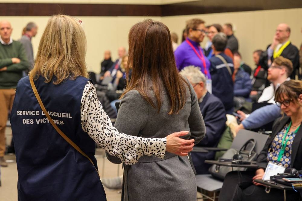 An aide guides victims to their seats during the start of the trial for the Brussels attacks, that took place on March 22, 2016, at the Justitia building in Brussels, Monday, Dec. 5, 2022. — Olivier Matthys/Pool/Reuters pic