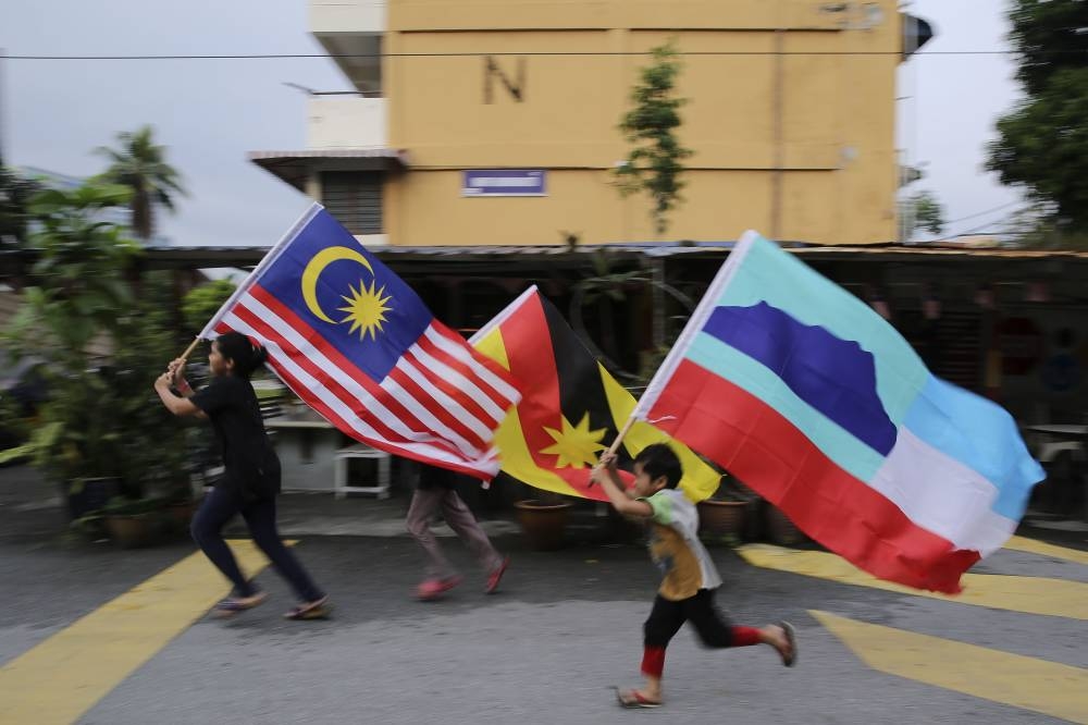 Children are seen hoisting Malaysia, Sarawak and Sabah flags as their run along Jalan Datuk Abdullah Yassin in Kampung Baru, Kuala Lumpur September 15, 2018. — Picture by Yusof Mat Isa