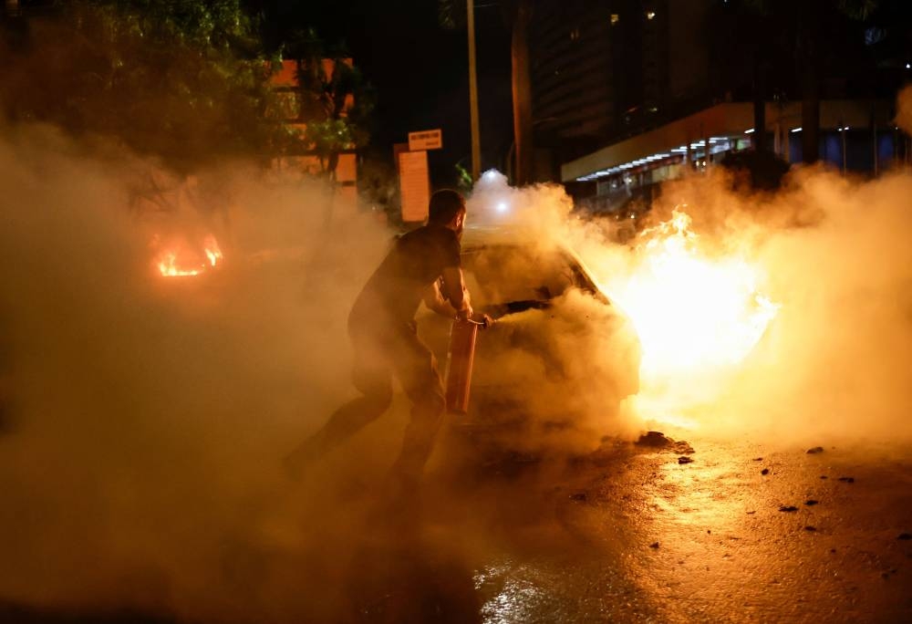 A firefighter works to put down a fire as supporters of Brazil's President Jair Bolsonaro protest after supreme court justice Alexandre de Moraes ordered a temporary arrest warrant of indigenous leader Jose Acacio Serere Xavante for alleged anti-democratic acts, in Brasilia, Brazil, December 12, 2022. — Reuters pic