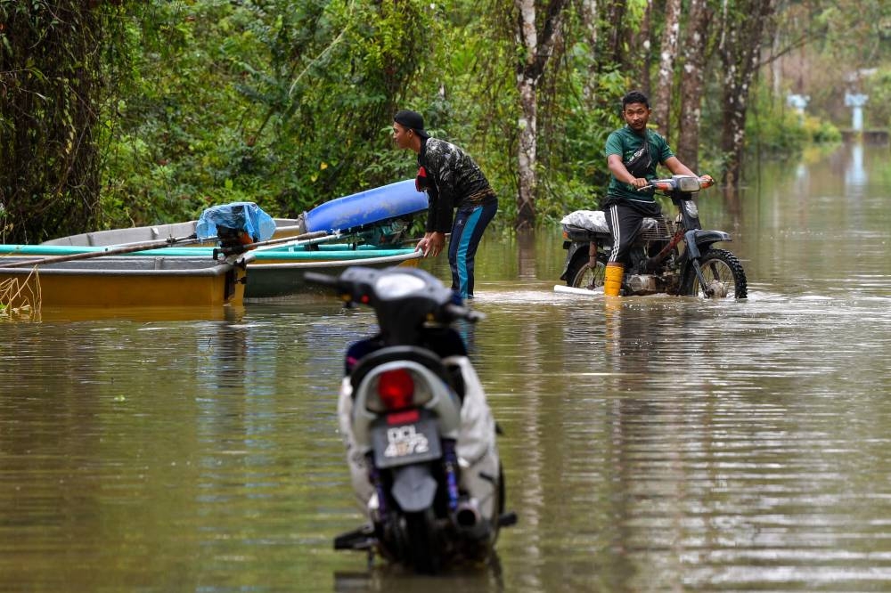 Flood victims use a boat as a mode of transport during the floods at Kampung Tersang, Rantau Panjang in Pasir Mas December 13, 2022. — Bernama pic