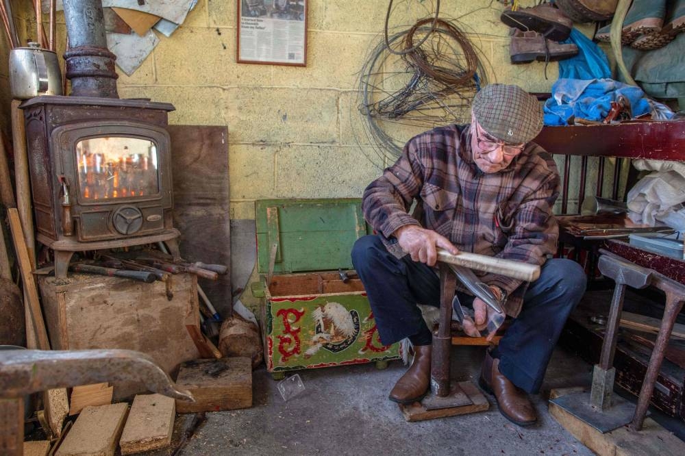 James Collins, one of the two remaining traditional Traveller tinsmiths in Ireland, works on November 23, 2022, in his workshop in Finglas, Dublin, where he makes tin and copper cups and billy cans. — AFP pic