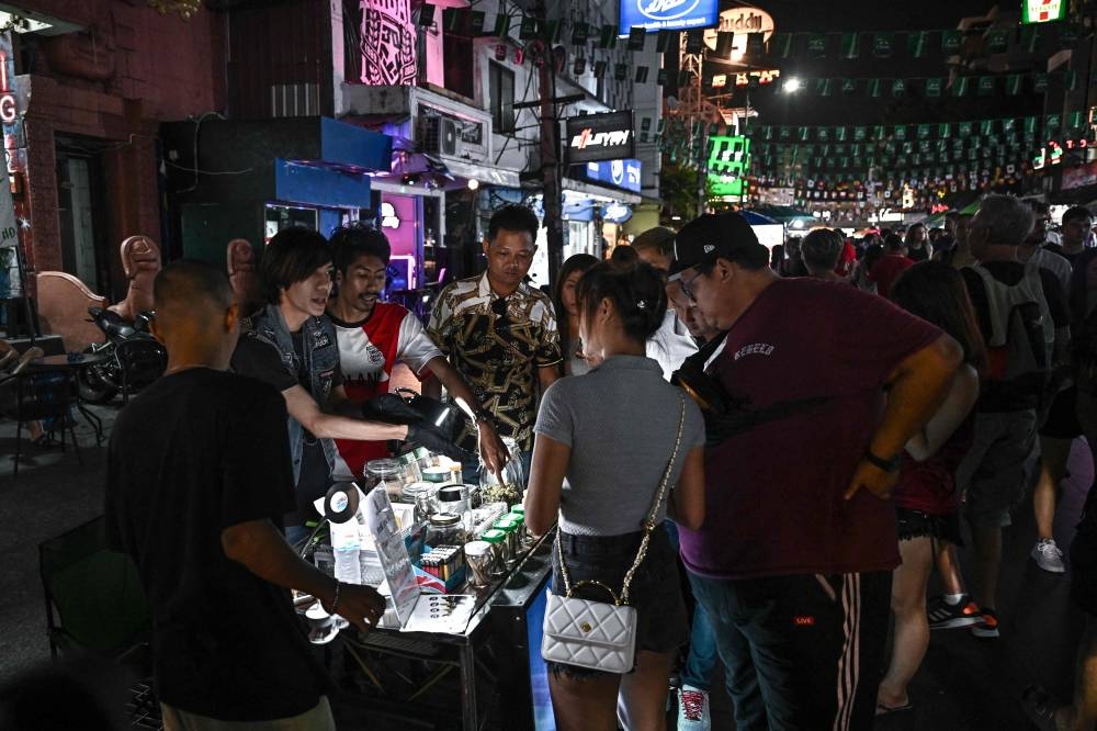 This photo taken on December 8, 2022 shows people buying cannabis buds at a stall on the popular tourist street Khaosan Road in Bangkok. — AFP pic