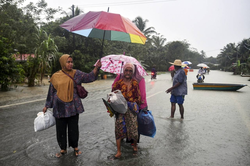 Some residents wading through floodwater to get to safety after their village was hit by floods due to continuous heavy rain in Kampung Tengkawan Hulu Terengganu, December 18, 2022. — Bernama pic