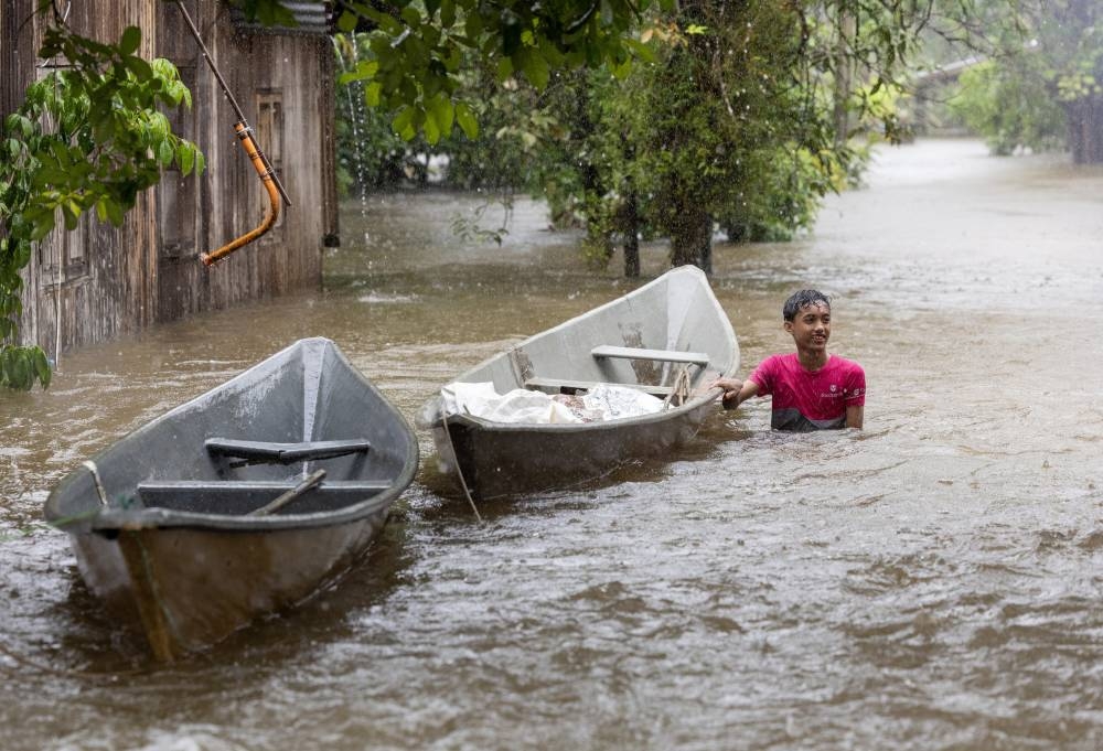 Mohd Amerudin Hassan, 15, using a boat to wade through the flood to buy food for his family in Pasir Mas, December 18, 2022. — Bernama pic