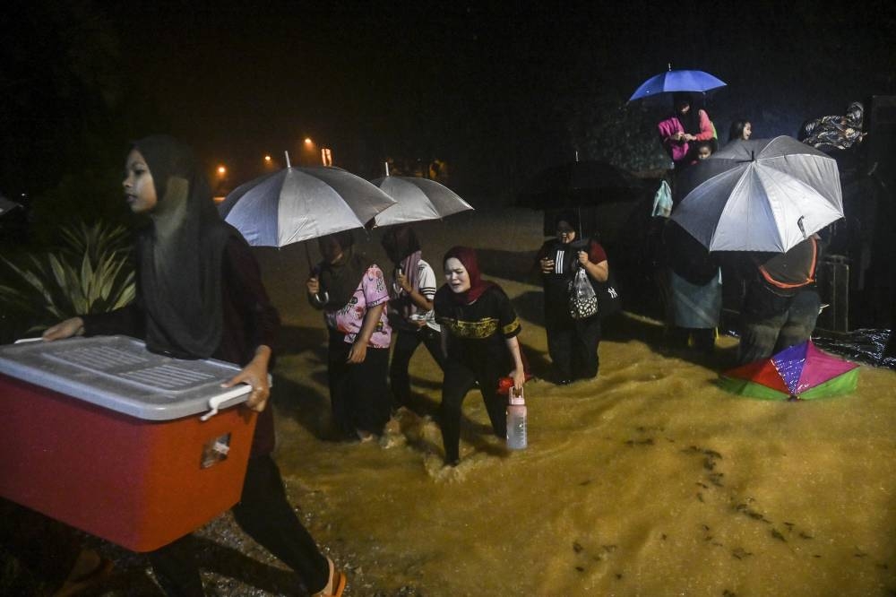 People wade through floodwaters to reach a temporary relief centre in Kampung Kepah, Hulu Terengganu December 18, 2022. — Bernama pic