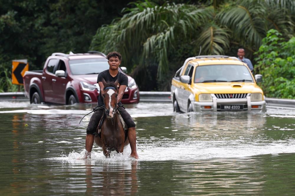 A villager rides a horse while wading through floods after the main road from Pasir Mas to Rantau Panjang was completely cut off, December 20, 2022. — Bernama pic 