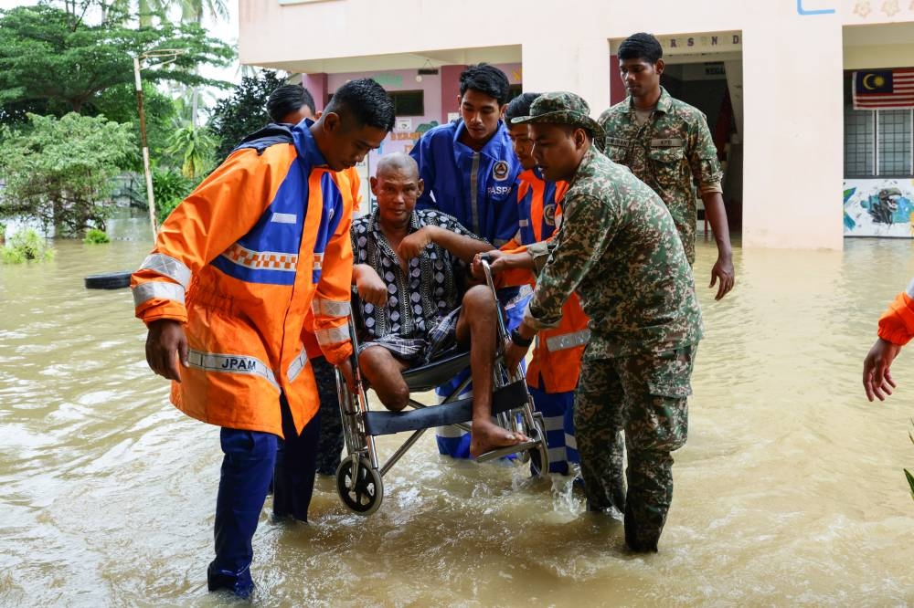 Members of the Malaysian Civil Defence Force and the Malaysian Armed Forces help a flood victim who is bedridden due to diabetes and high blood pressure to be sent to hospital for treatment at the Mangkok National School relief centre, December 20, 2022. — Bernama pic 