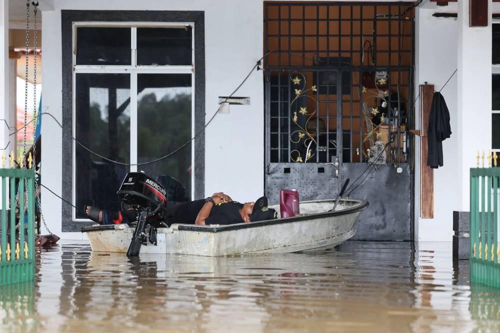 A resident of Taman Desa Tanjung Damai, Gong Badak in Terengganu is pictured resting in a boat after helping residents remove items from their homes, December 21, 2022. — Bernama pic 