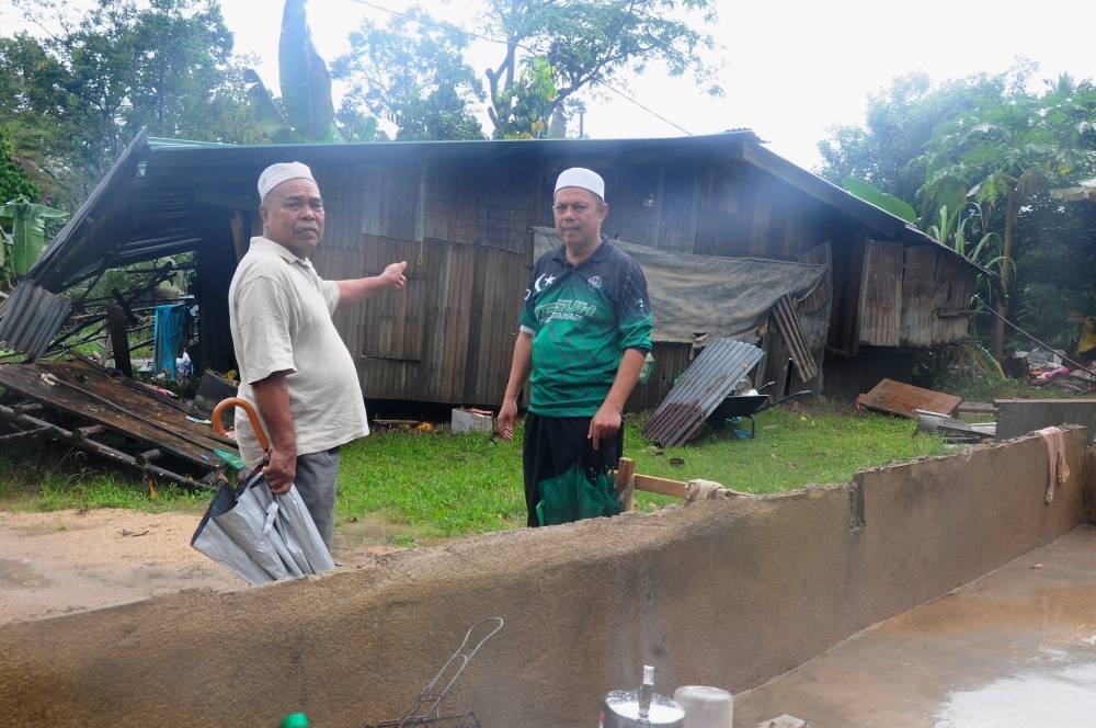 Resident Che Hussin Che Ali, 72, (left) with Hulu Besut State Legislative Assembly supervising officer Mat Daik Mohamad survey the former’s house that was affected by floods at Kampung Bekok Hulu Besut, Jertih December 21, 2022. — Bernama