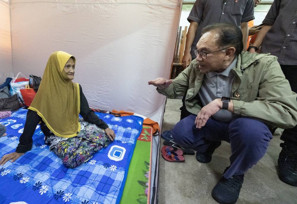 Prime Minister Datuk Seri Anwar Ibrahim speaks to a flood victim during a visit to the temporary relief centre (PPS) at Sekolah Menengah Kebangsaan Tengku Panglima Raja in Pasir Mas December 21, 2022. — Bernama pic