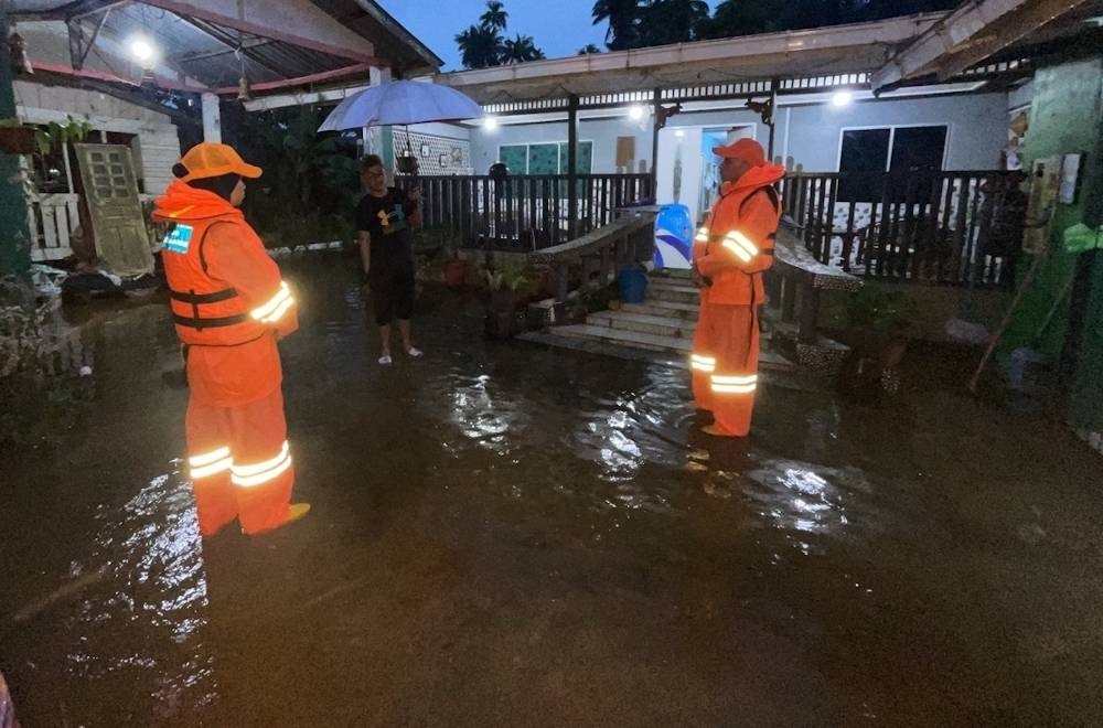 Civil Defence Force (APM) personnel speak to a flood victim in Kampung Bedaun December 23, 2022. — Picture courtesy of Civil Defence Force