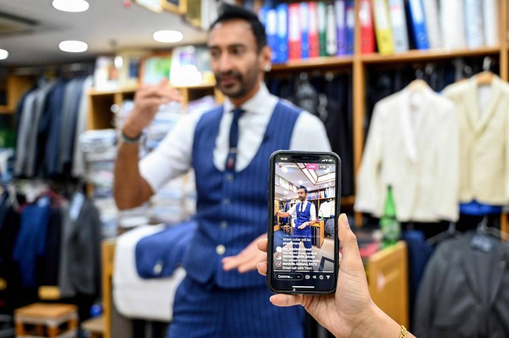 In this photo taken on October 25, 2022, Roshan Melwani of Sam's Tailor is filmed by his team as he talks to a client in the US during a video call at his shop in Hong Kong.  — AFP pic