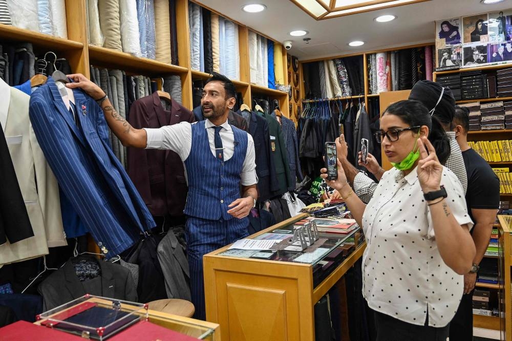 In this photo taken on October 25, 2022, Roshan Melwani of Sam's Tailor works alongside his team as he talks to a client in the US during a video call at his shop in Hong Kong. — AFP pic