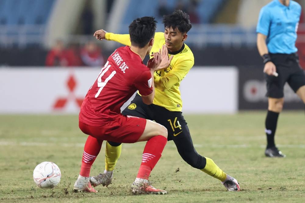 Malaysian footballer Muhammad Mukhairi Ajmal Mahadi (right) in action against a player from Vietnam during the Group B match in the 2022 AFF Cup at the My Dinh National Stadium, Hanoi December 27, 2022. — Bernama pic