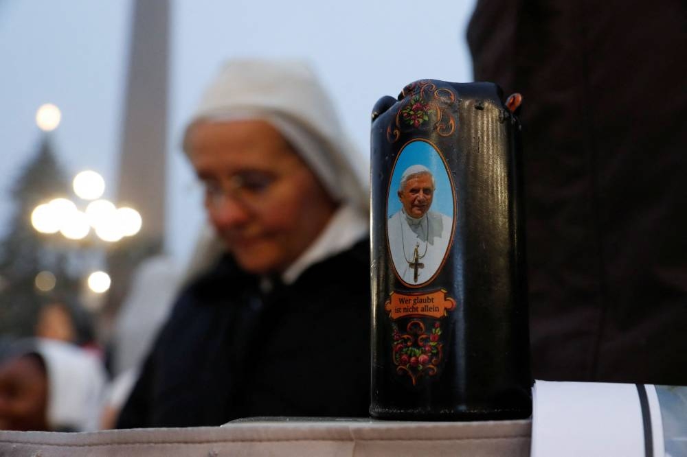 A nun prays next to a candle with a picture of former Pope Benedict, on the day of his funeral at the Vatican, January 5, 2023. — Reuters pic