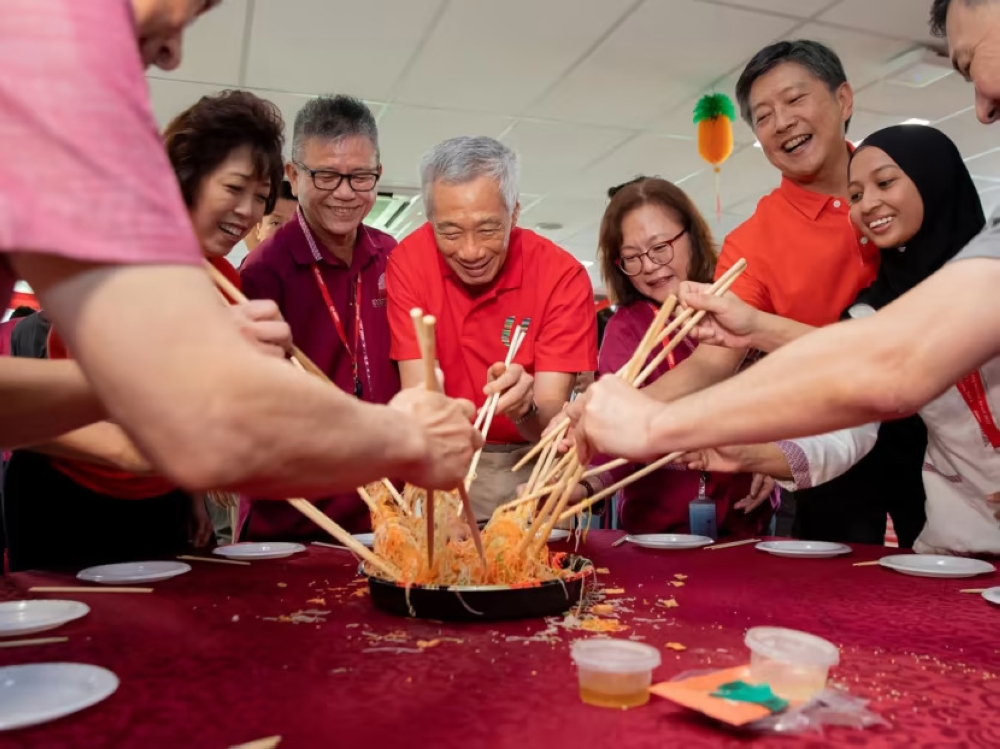 Prime Minister Lee Hsien Loong taking part in the tossing of yusheng at the Woodlands Integrated Transport Hub on Jan 21, 2023. — TODAY pic