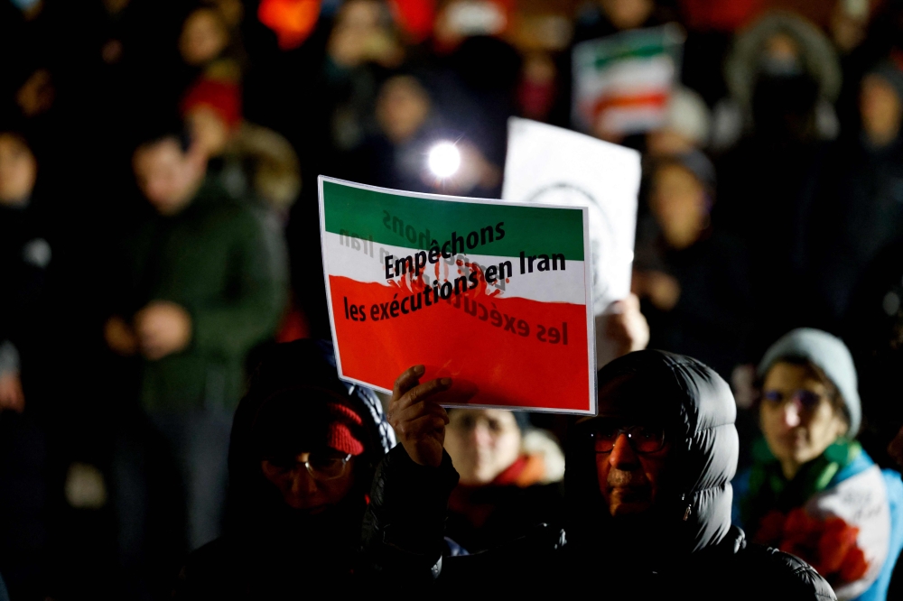 A protester holds a banner reading ‘Let's prevent executions in Iran’ on the Trocadero Esplanade in Paris January 16, 2023. — AFP pic