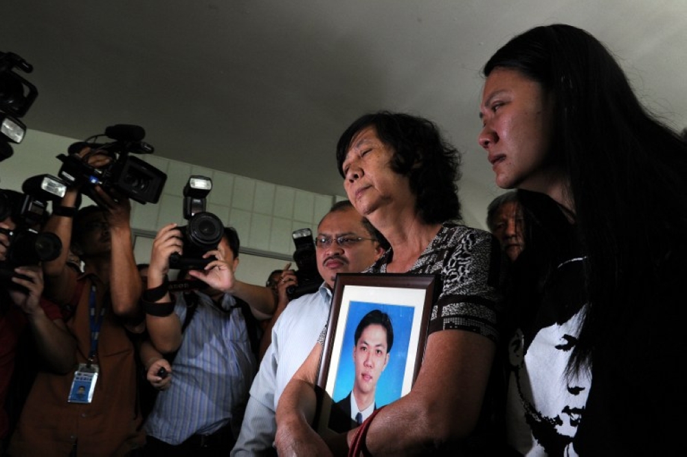 Teoh Beng Hock’s mother Teng Shuw Hor (centre) and sister Teoh Lee Lan (right) react as they leave the Shah Alam Criminal court while holding his portrait in the outskirts of Kuala Lumpur January 5, 2011. ― AFP pic