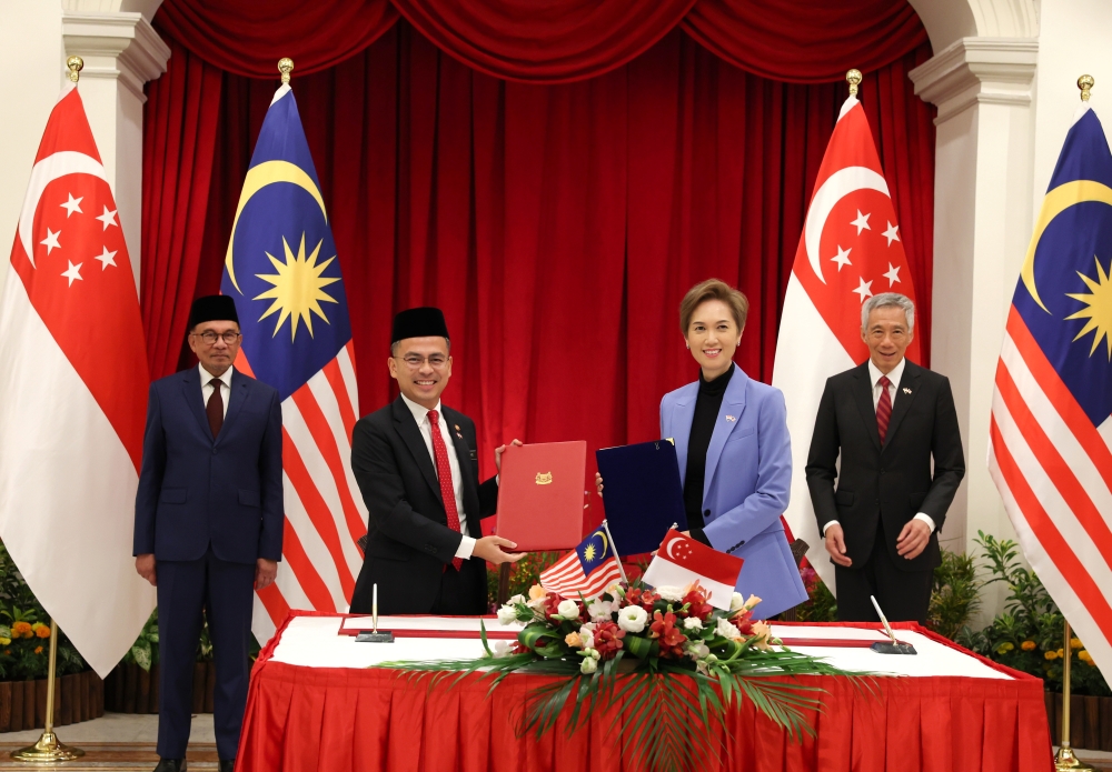 Prime Minister Datuk Seri Anwar Ibrahim (left) and his counterpart from Singapore Lee Hsien Loong (right) witness Memorandum of Understanding on promoting Cooperation in Data, Cyber Security and Digital Economy signing ceremony between Malaysian Communications and Digital Minister Fahmi Fadzil (2nd left) and his counterpart from Singapore, Josephine Teo (2nd right) at the Istana, Singapore January 30, 2023. — Bernama pic