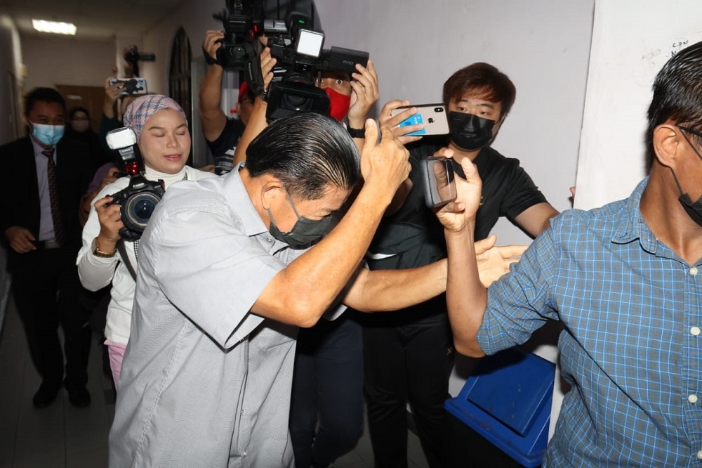 Accused Datuk Teo Wee Cheng (centre) being escorted into the courtroom to stand trial over for allegedly accepting RM12.875 million linked to the Jana Wibawa scheme at the Johor Baru Sessions Court. Feb 22, 2023. — Picture by Ben Tan