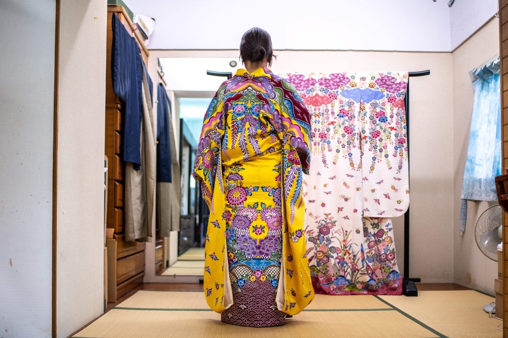 An employee of artisan Toma Chinen, who inherited the workshop of one of three Bingata-making families that once served Ryukyu royalty, wearing a Bingate in Naha, in Japan's Okinawa Prefecture August 22, 2022. — AFP pic