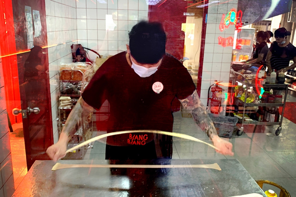 Hand-pulling each piece of dough into noodles or “noods” as the team calls them.