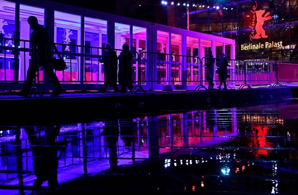 Visitors are reflected in rain water as they leave the Berlinale Palast theatre during the Berlinale, Europe’s first major film festival of the year, in Berlin on February 20, 2023. — AFP pic