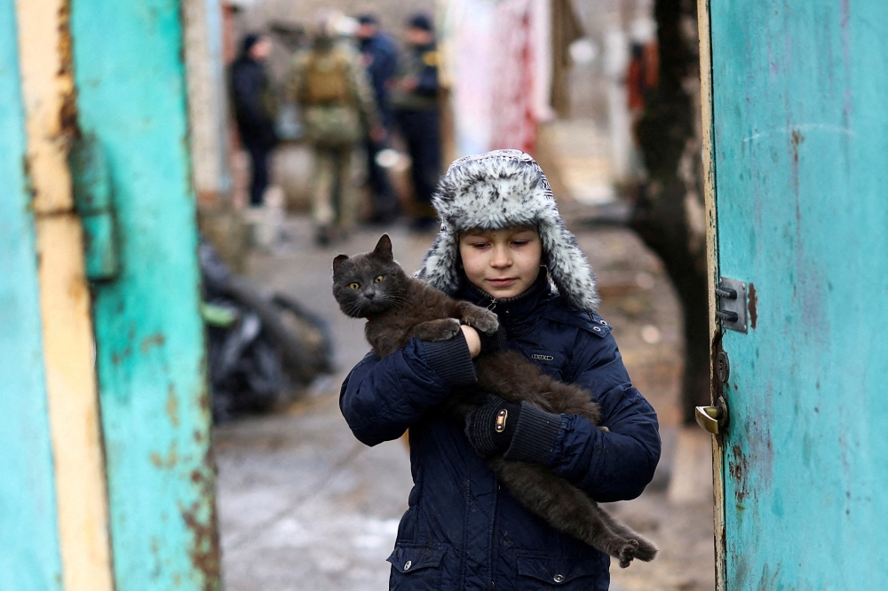 A boy carries his cat, while being evacuated, as Russia’s invasion of Ukraine continues. — Reuters pic