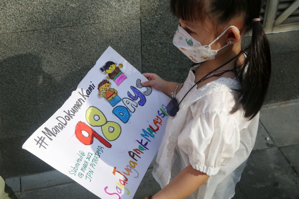 Lin Peak Yee's daughter, one of the overseas-born children holding a poster asking for her documents on her on her Malaysian citizenship in JPN Putrajaya June 10, 2022. — Picture by Choo Choy May .