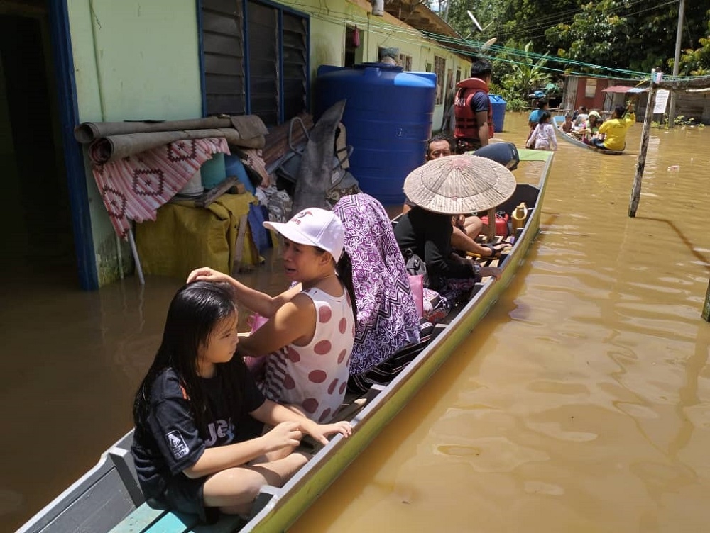 The longhouse residents board a longboat to the evacuation centre. — Picture courtesy of Fire and Rescue Dept