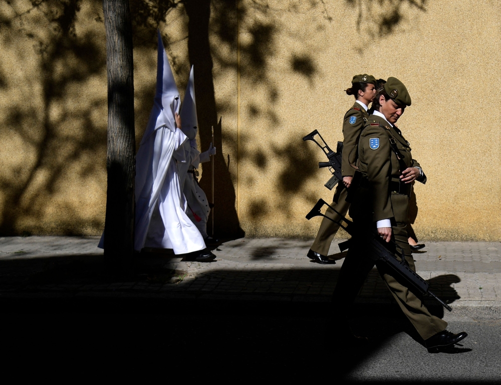 Penitents of La Paz brotherhood and female soldiers walk to a church prior to participating in the Palm Sunday procession, in Seville on April 2, 2023. — AFP pic