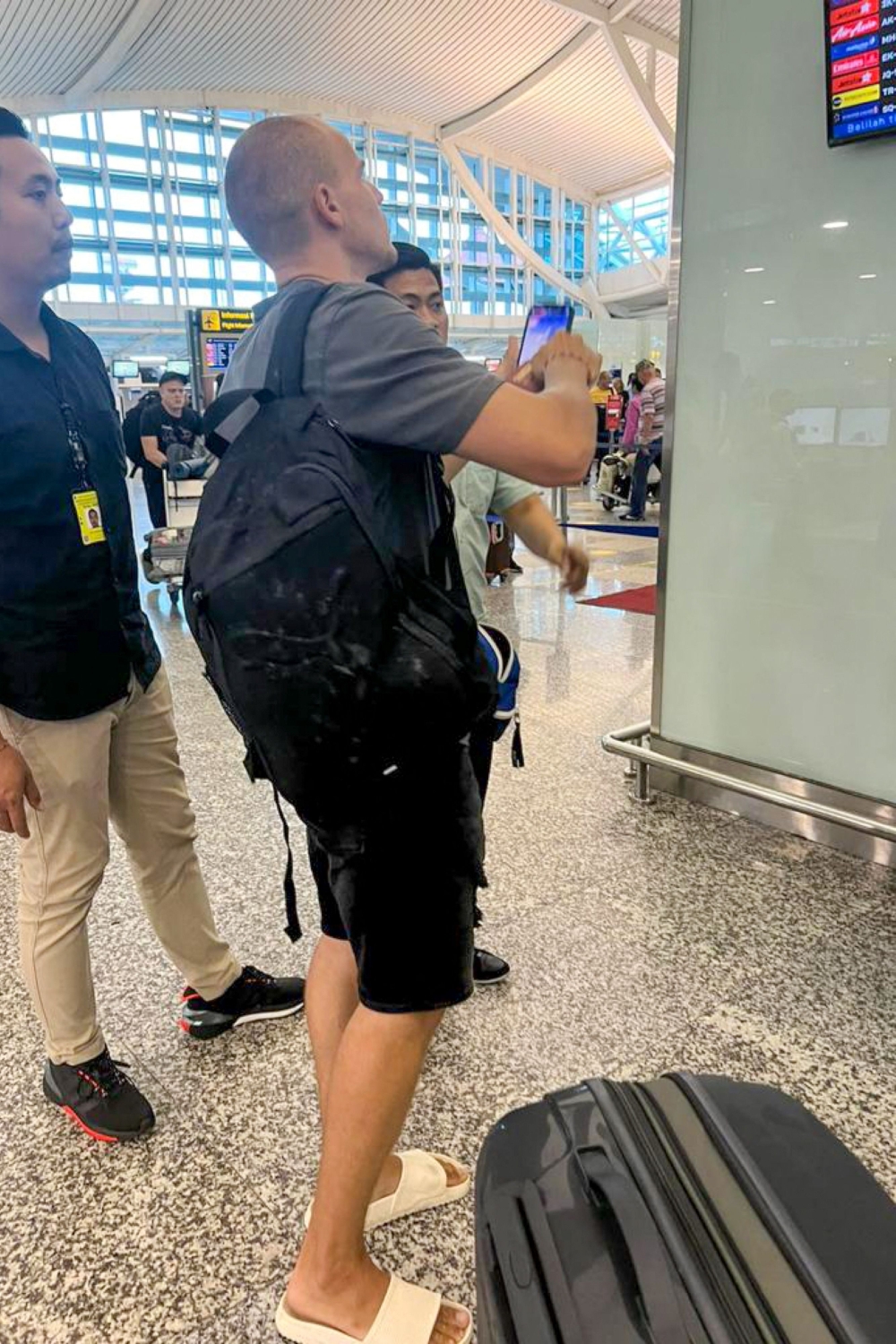 This handout picture released on April 5, 2023 by Bali Immigration Office shows immigration officers escorting Russian Yuri Chilikin at the airport in Denpasar. — AFP pic/Bali Immigration Office