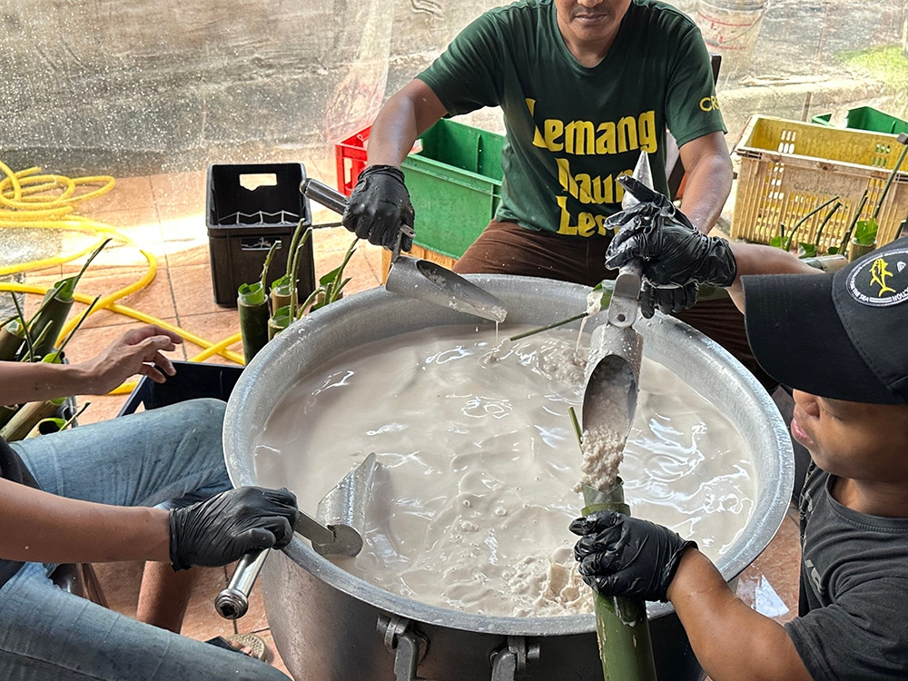 The mixture of 'santan' and the glutinous rice grains are poured into the 'daun lerek'-lined bamboo cyliner.