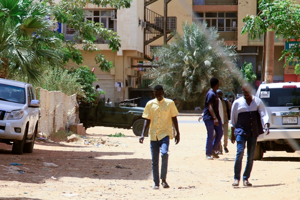 People walk past a military vehicle in Khartoum on April 15, 2023, amid reported clashes in the city. — AFP pic