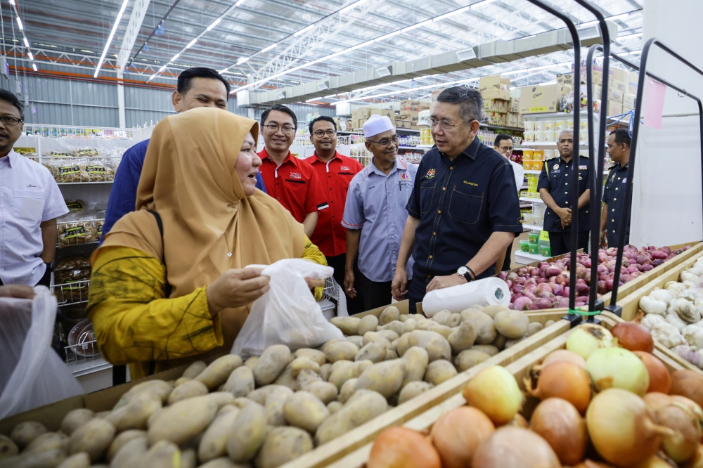 Domestic Trade and Cost of Living Minister Datuk Seri Salahuddin Ayub (right) speaks to a customer during a survey carried out by the ministry at a supermarket in Jertih April 17, 2023. — Bernama pic