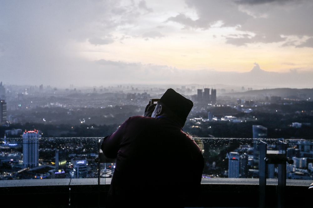 A religious official prepares to observe the evening sky for the crescent moon, at the KL Tower on March 22, 2023. — Photo by Hari Anggara