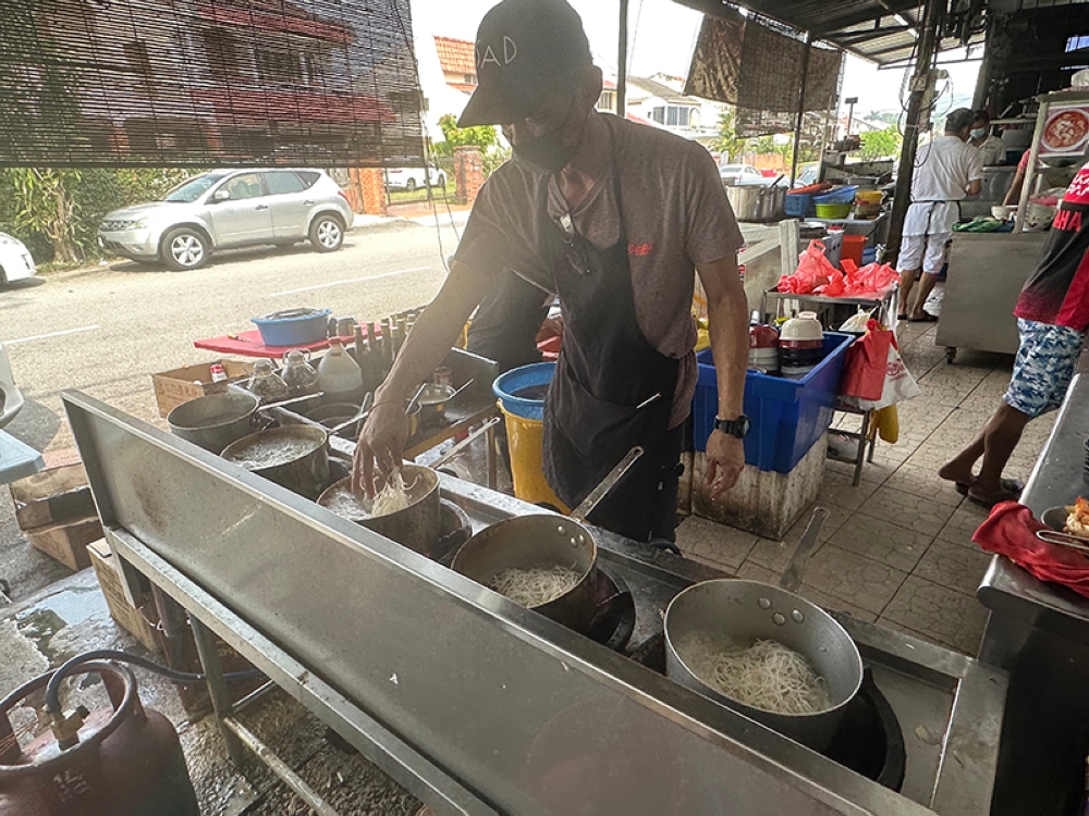 The owner tries to cut down waiting time with his assembly of pots over a super hot fire.